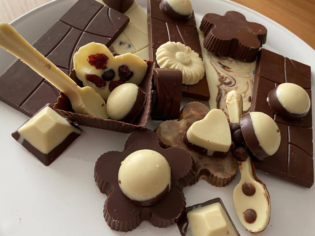Chocolate bars in different shapes made with different molds. Use of milk and white chocolate for flavor and decoration. The chocolates are layered but there are also chocolate swirls. Toppings such as cranberries are used as well