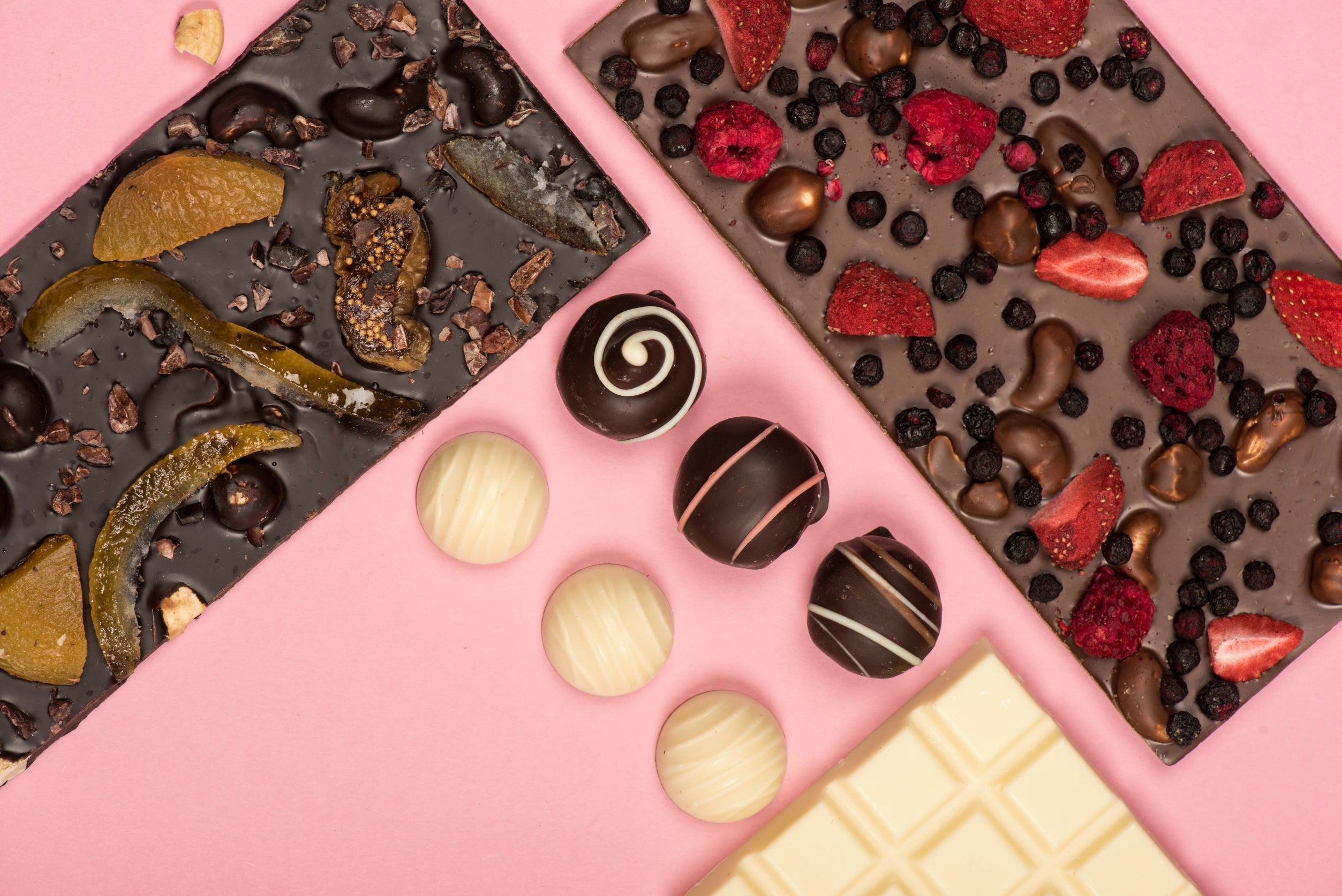 Chocolate bars and bonbons decorates with white chocolate and with colorful toppings and inclusions